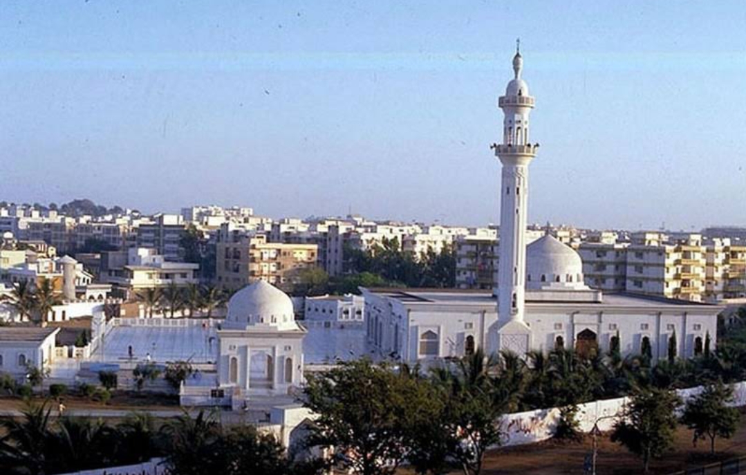 Wide elevated view of Bait ul Mukarram showing the full compound and minaret rising above a low-rise Karachi