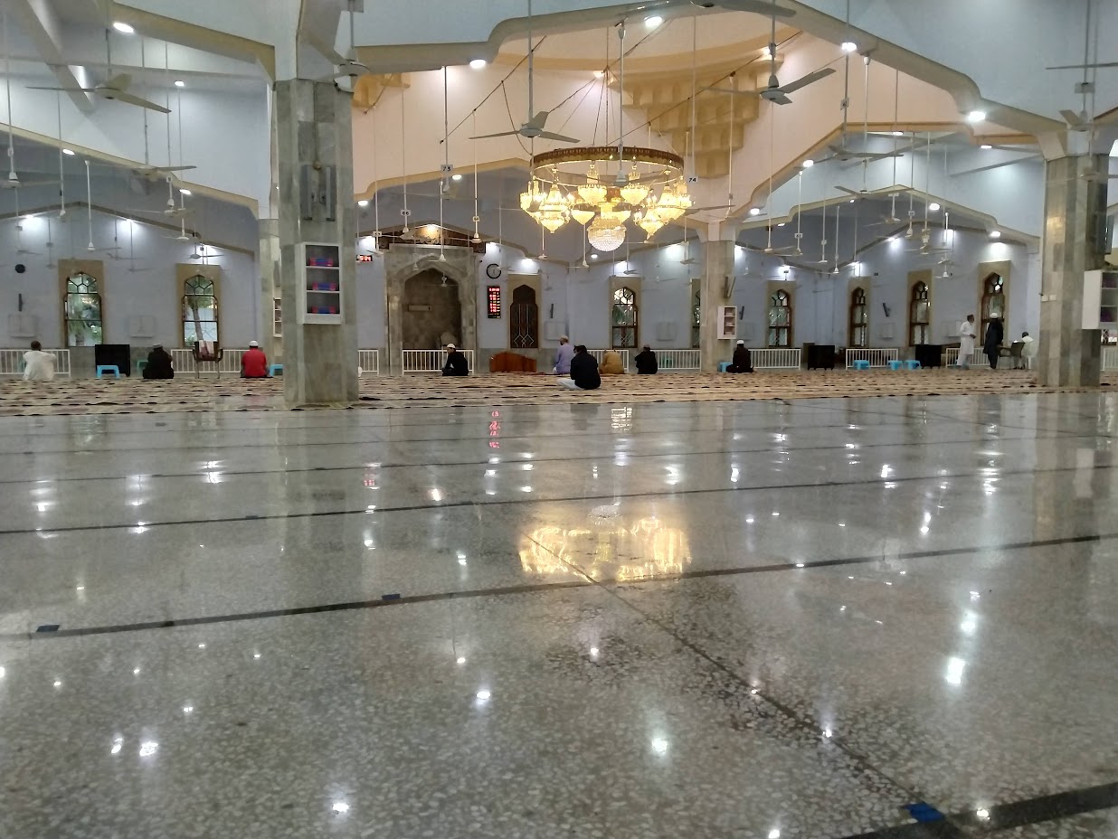 Prayer hall at Bait ul Mukarram with worshippers after prayer — chandelier and reflective marble floor