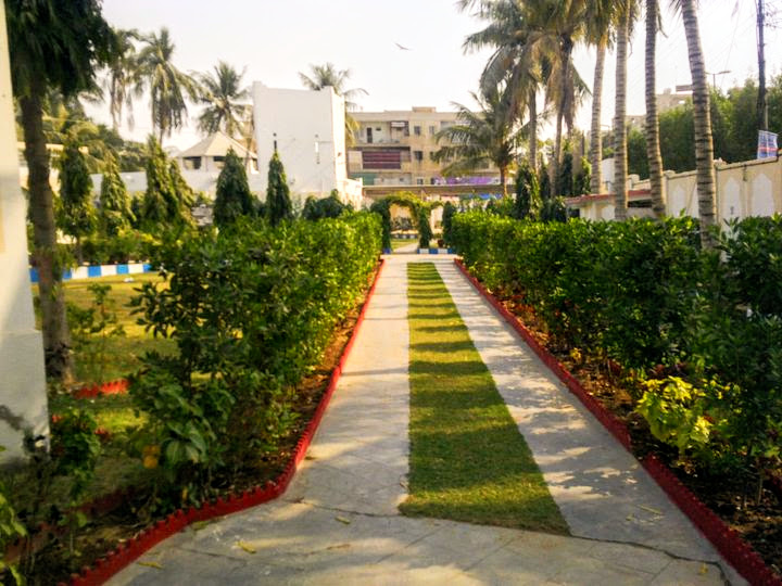 Manicured garden path inside Bait ul Mukarram compound — hedgerows, palms, and walkway