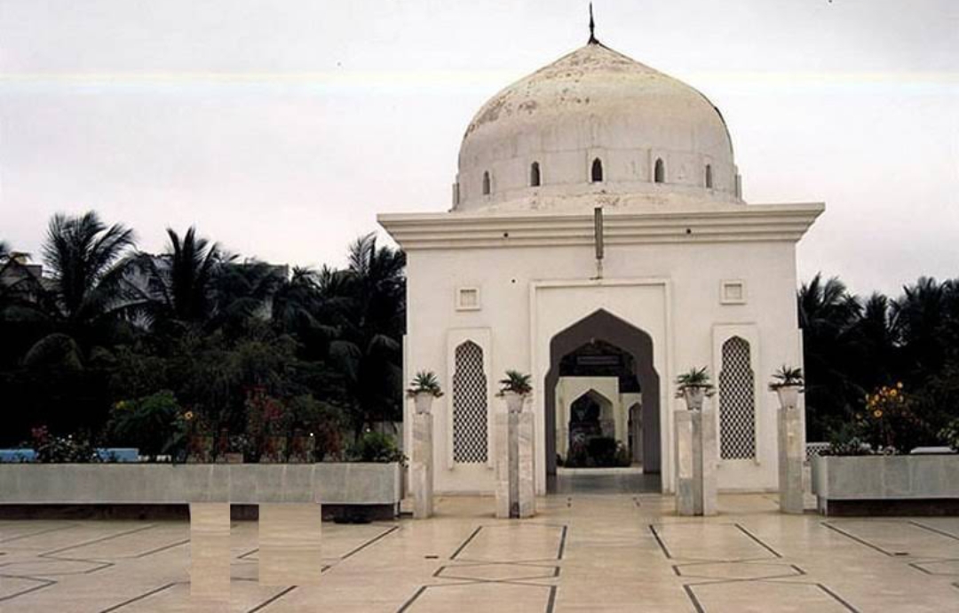 View from University Road gate of Bait ul Mukarram in the 1990s — the old secondary dome and arched entrance visible, palm trees and open grounds