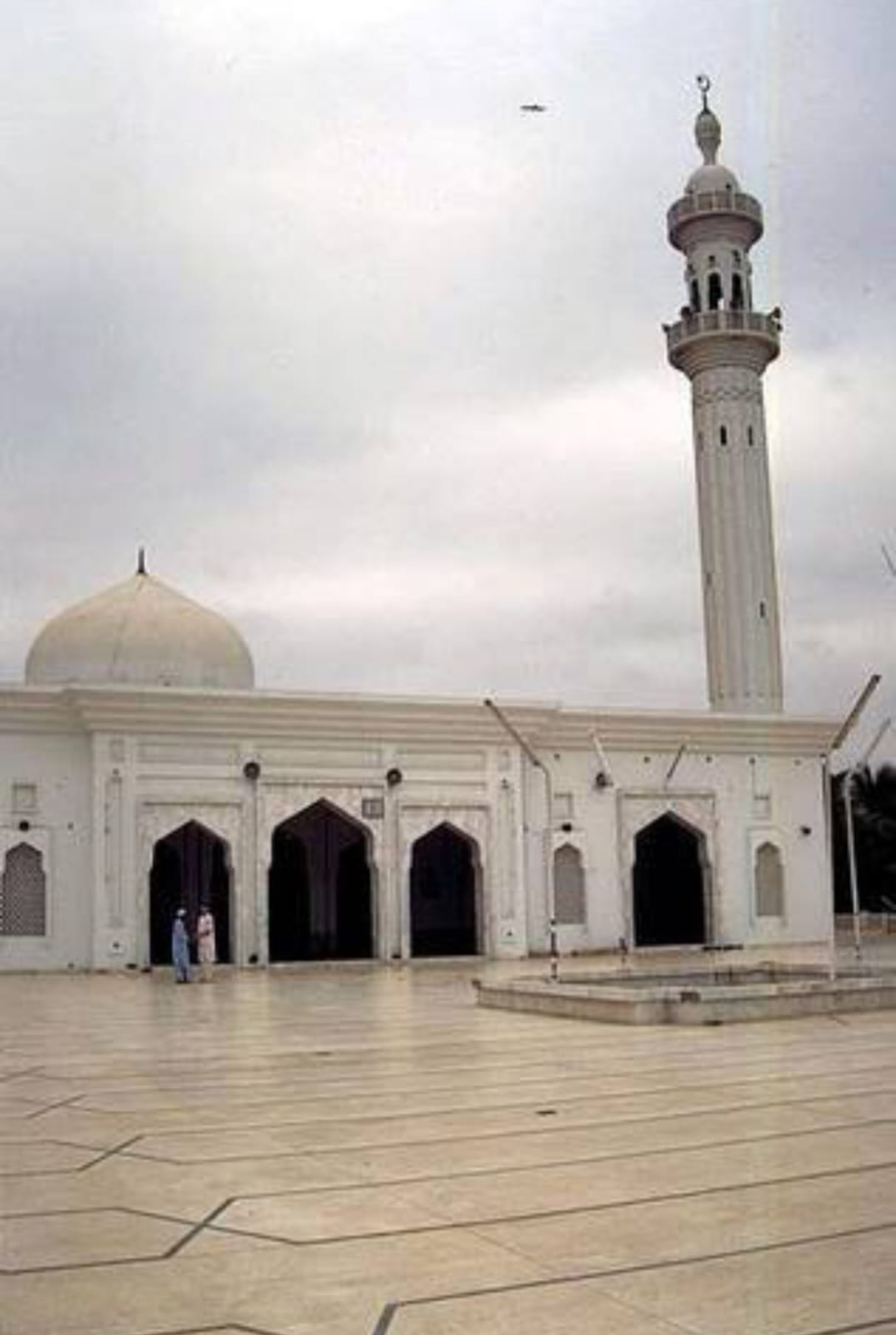 The sahn and main facade of Bait ul Mukarram in the 1990s — two worshippers at the arched entrance, minaret above