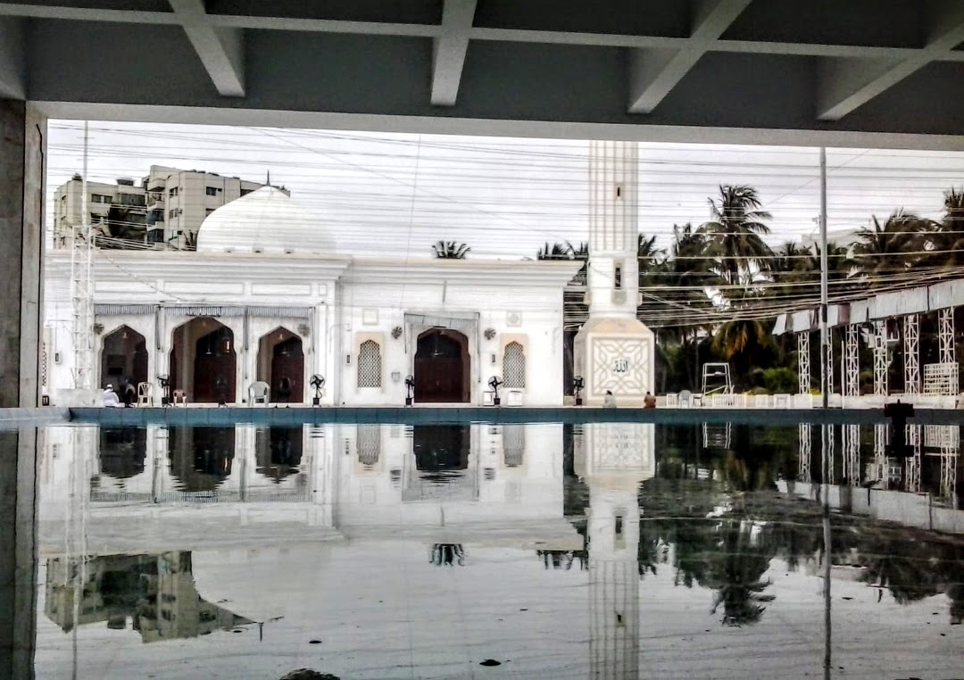The wuzu pool at Bait ul Mukarram — the mosque dome and minaret reflected in the still water, now dismantled