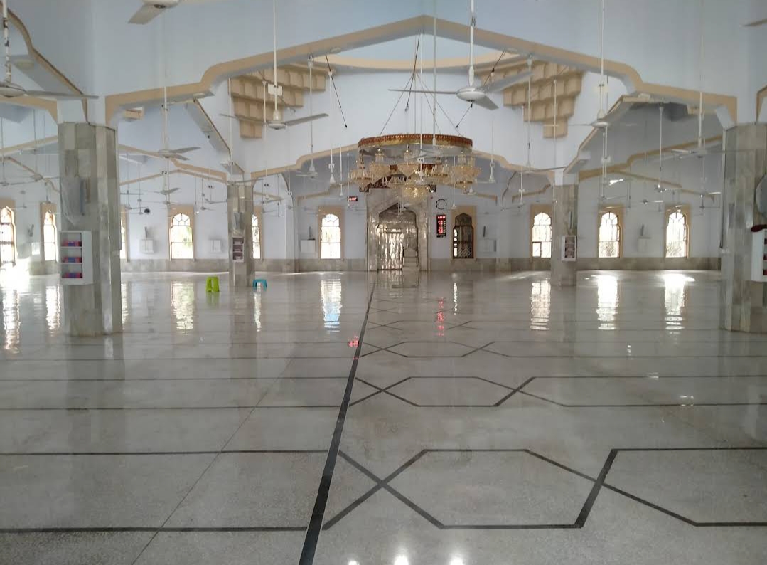 Wide view of the main prayer hall looking toward the mihrab — marble columns, arched windows, full length