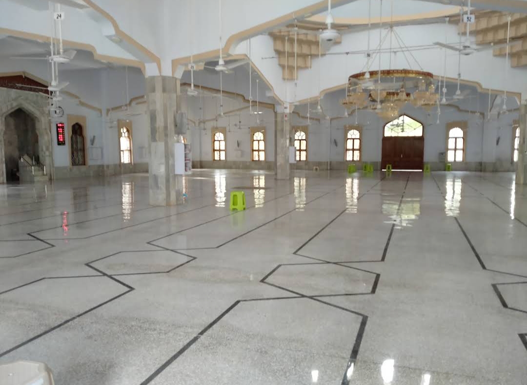 Evening in the prayer hall — worshippers after Isha, chandelier glow reflected in the marble floor